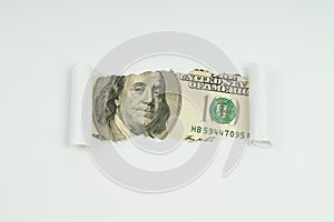 An image of a 100 dollar bill is visible in the torn hole of a sheet of paper