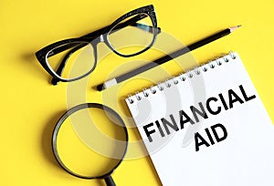 Business and finance concept - notebook with pencils glasses magnifier. Financial Aid