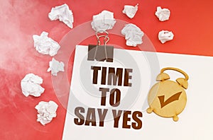 On a red background in smoke, crumpled paper and a sheet with the inscription - TIME TO SAY YES