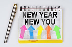 On a white background lie a pen and a notebook with the inscription - NEW YEAR NEW YOU