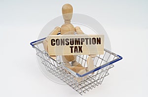 A wooden man sits in a shopping basket, holding a sign in his hands - Consumption Tax photo