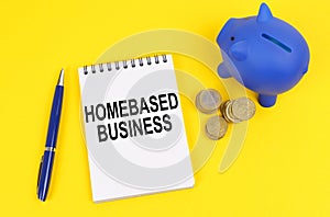On a yellow surface, a piggy bank, coins and a notepad with the inscription - Homebased business