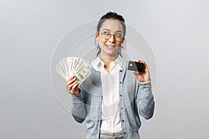 Business, finance and investment concept. Thoughtful smiling young asian rich woman in glasses, bite lip curious, look