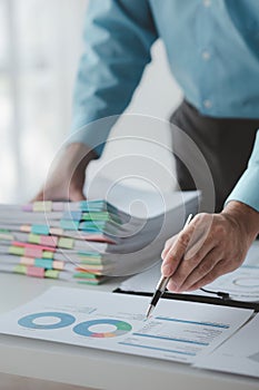 A business finance man is reviewing a company's financial documents prepared by the Finance Department for a meeting.