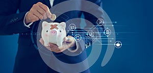 Business financing accounting banking concept, Businessman insert coin into a injury piggy bank with icon banking and payment.