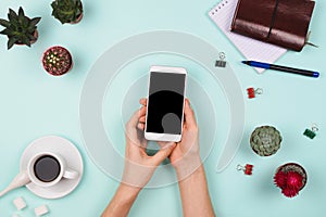 Business flatlay arrangement with woman`s hands holding smartphone with black copyspace and other stationary and office accessori