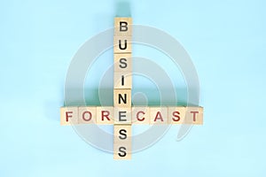 Business forecast or forecasting strategy concept. Wooden block crossword puzzle flat lay in blue background.