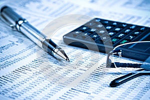 Business fountain pen, calculator and glasses on financial chart