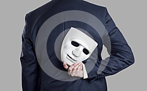 Businessman hide the mask in hand behind his back.