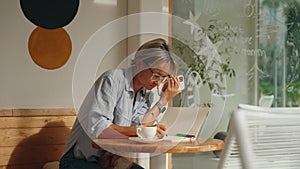 Business freelance woman using smartphone for browsing Internet, reading and texting while sitting on table in cafe