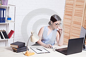 Business girl in glasses sits in an Office at a computer folder paper