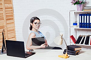 Business girl sits at a computer in the Office paper folders