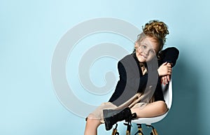 Business girl in stylish black jacket ang beige dress sits in office chair showing thumb up with smile and holding another hand