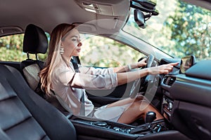 Business girl in summer city, sitting in car, hand selects mode on touch screen display, route selection, enabling