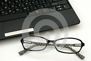 Business glasses near a laptop keyboard