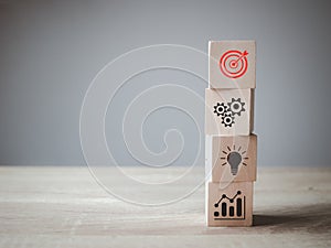 Business goal target achievement concept of business strategy and action plan on wooden cube block stacking with icon