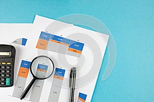Business graphs, charts and magnifying glass on table