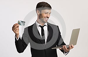Business guy holding laptop and credit card over white background