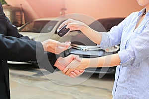 Business hand giving a key of buyer at rental car.