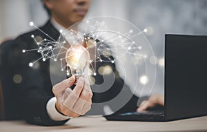 Business hand holding light bulb and working with computer on the desk, Creativity and innovation are keys to success.Concept of n