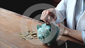 Business hand putting gold coin into pink piggy bank on brown cement wall background, Saving money for future plan and retirement