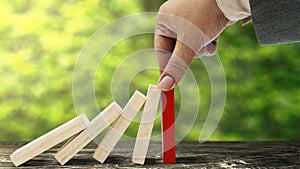 Business hand stopping a falling wooden dominoes