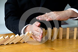Business hand stops domino continuous overturned meaning that hindered business failure. Stop over this business failure concept