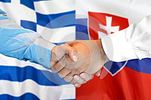Podanie ruky na pozadí vlajky Grécka a Slovenska