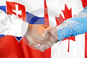 Podanie ruky na pozadí vlajky Slovenska a Kanady