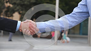 Business handshake with blurred city background. Two businessmen greeting each other in urban environment. Shaking of