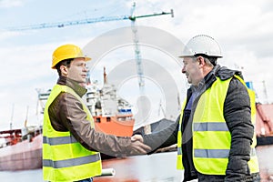 Business handshake in a shipyard. Shipbuilding industry