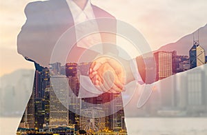 Two businessman and business women shaking hands on city background