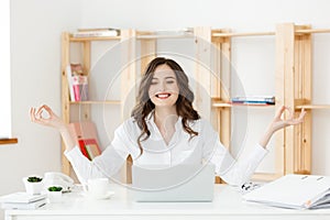 Business and Health Concept: Portrait young woman near the laptop, practicing meditation at the office desk, in front of