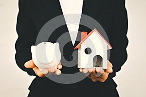 Business holding white piggy bank and little house