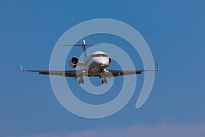 Business jet airplane flying on a high altitude above the blue cloudless sky.