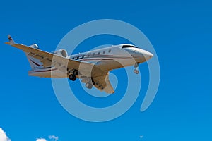 Business jet airplane flying on a high altitude above the blue cloudless sky.