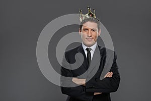 Business king. Confident businessman in crown standing isolated