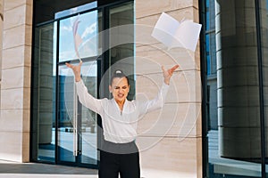 Business lady with anger throws papers in different directions against the background of the business center