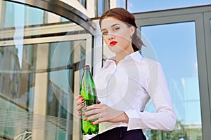 Business lady with a bottle of clean water against the background of an office building. Water