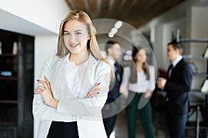 Business lady with crossed hands in front of discussing coworkers