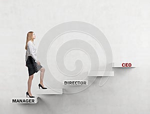 A business lady is going up the corporate ladder from the manager to CEO. Concrete background.