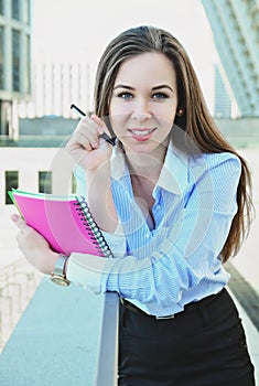 Business lady leans on the railing, smiles, looks at the camera