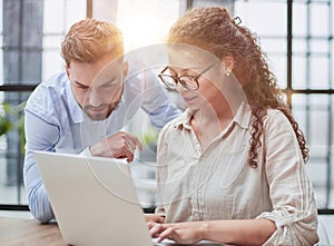 business lady looking at laptop with her colleague in the office