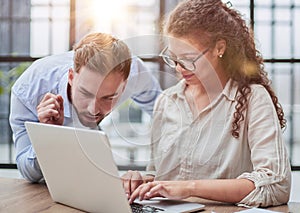 business lady looking at laptop with her colleague in the office photo