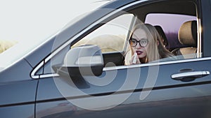 Business lady looking in rear view mirror and applying red lipstick in car