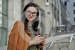 Business lady. Portrait of a young beautiful happy caucasian woman holding her smartphone and smiling at camera while