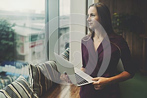 Businesswoman with laptop next to office window