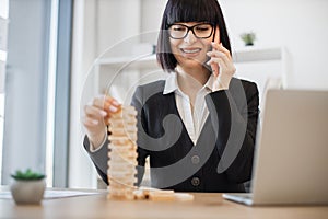 Business lady relaxing with jenga while talking on phone