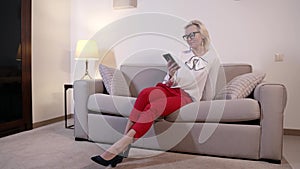 business lady is sitting in apartment and using smartphone, checking email and message in social nets