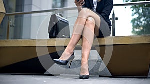 Business lady sitting on bench, writing message to partner who late for meeting